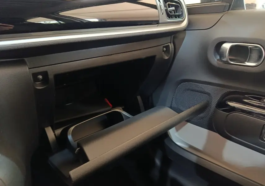 Intérieur de la Citroën C3 2020, vue côté passager montrant la boîte à gants ouverte et le panneau de porte noir et blanc.