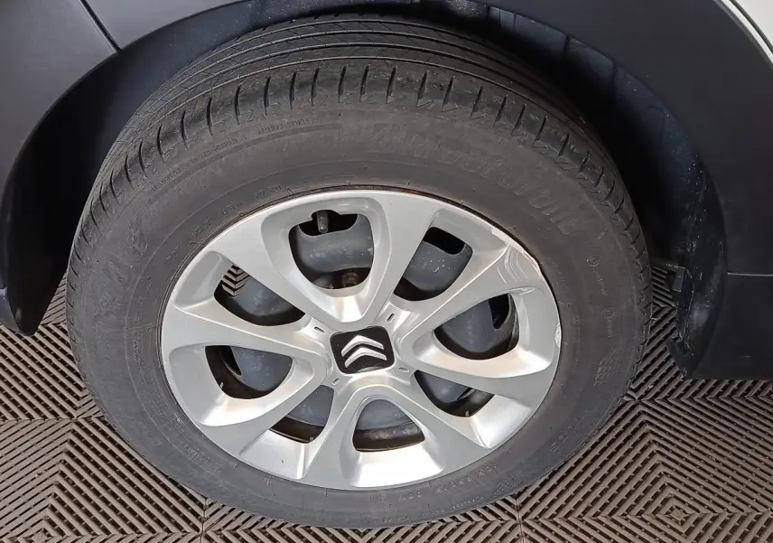 Gros plan sur la roue arrière droite d'une Citroën C3 blanche, avec jante alliage et garde-boue noir.