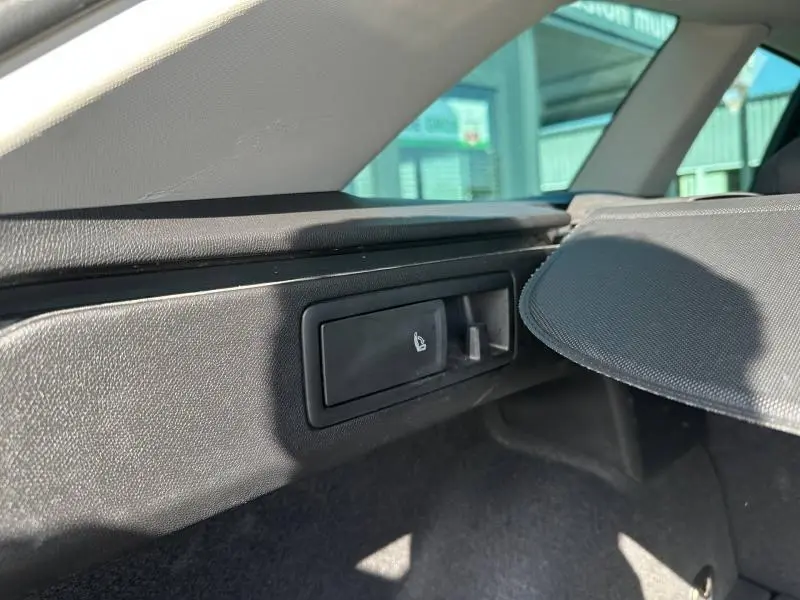 Détail du coffre du SEAT LEON ST 2025 gris métallisé, montrant le levier rabattable des sièges arrière côté droit.