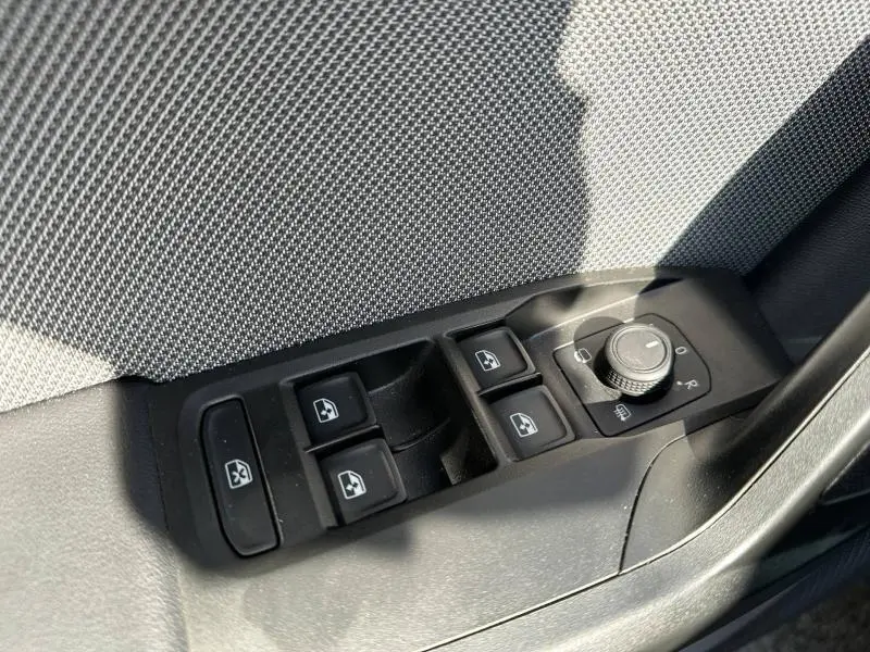 Gros plan sur les commandes des vitres et des rétroviseurs côté conducteur du SEAT LEON ST gris magnétique 2025.