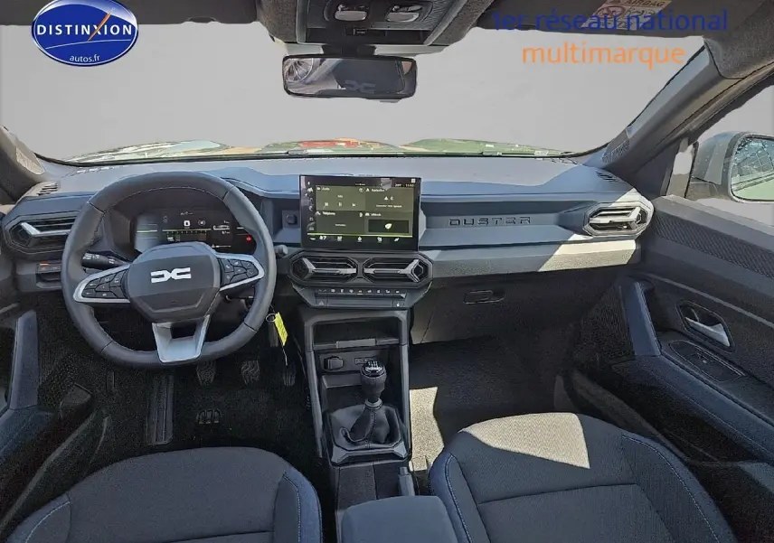Vue intérieure avant du Dacia Duster 2025 montrant le volant multifonction, écran tactile et levier de vitesses manuel.