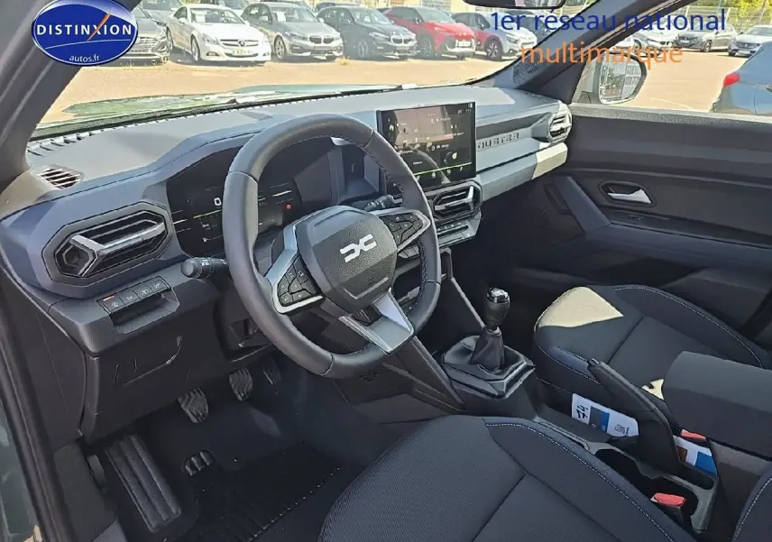 Intérieur avant du Dacia Duster 2025 vert kaki, volant multifonction et écran tactile au centre du tableau de bord.