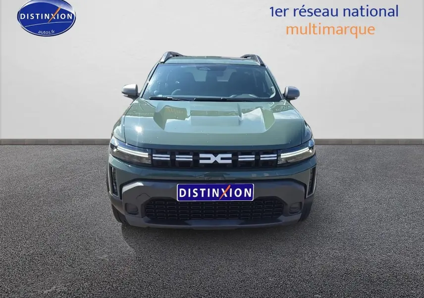 Vue de face d'un Dacia Duster 2025 vert kaki avec calandre moderne et barres de toit visibles.