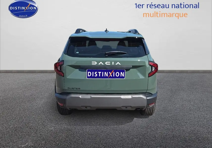 Vue arrière du Dacia Duster vert kaki 2025 avec bouclier gris et barres de toit visibles sur fond neutre.