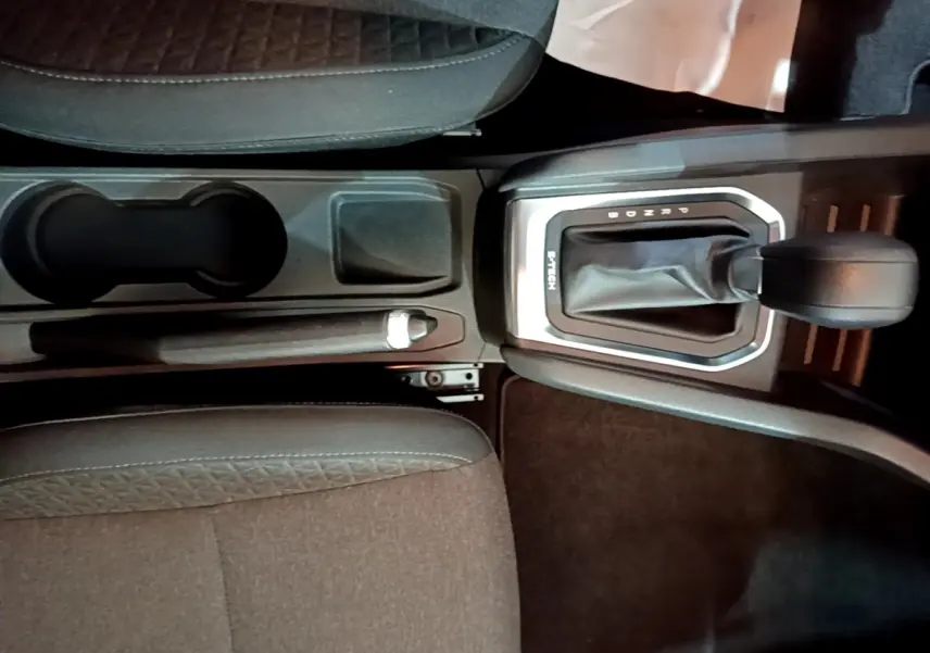 Vue rapprochée de la console centrale de la Renault Clio Business E-TECH 140 gris foncé, avec levier de vitesse automatique et frein à main.