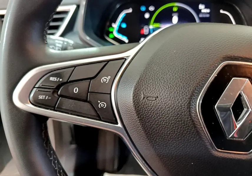 Gros plan sur le volant cuir synthétique de la Renault Clio Business E-TECH 140, avec commandes de régulateur de vitesse visibles.