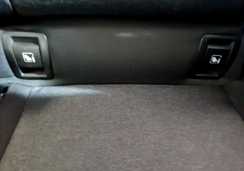 Détail des commandes de rabattement des sièges arrière sur la banquette d'une Renault Clio Business E-TECH 140 gris foncé.