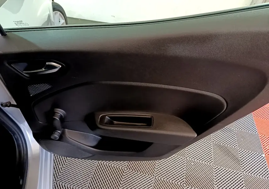 Vue intérieure côté gauche de la porte arrière d'une Renault Clio gris foncé avec poignée de fenêtre manuelle.