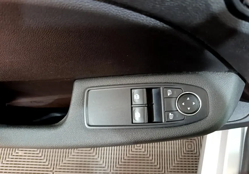 Commande des vitres électriques et réglage des rétroviseurs sur la portière côté conducteur d'une Renault Clio gris foncé.