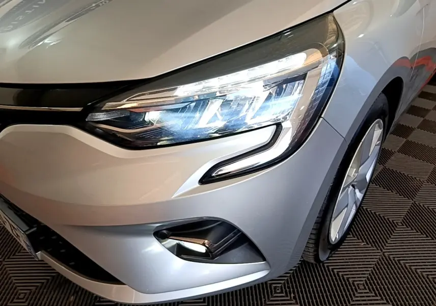 Gros plan sur l'avant droit gris foncé de la Renault Clio Business E-TECH 140 2022, avec phares LED allumés.