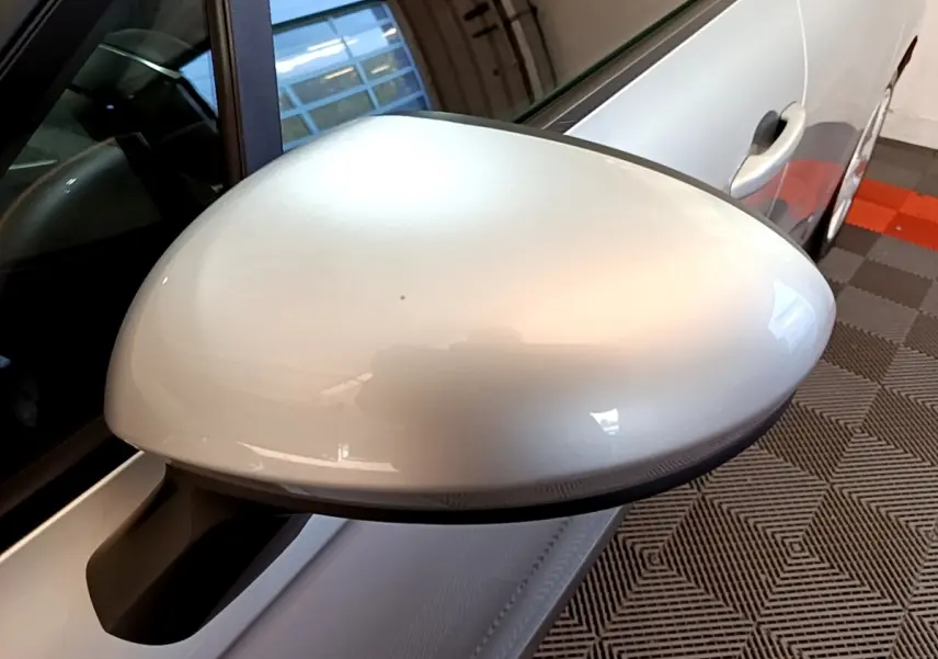 Gros plan sur le rétroviseur droit gris clair d’une Renault Clio Business E-TECH 140 2022, avec porte et vitre partiellement visibles.