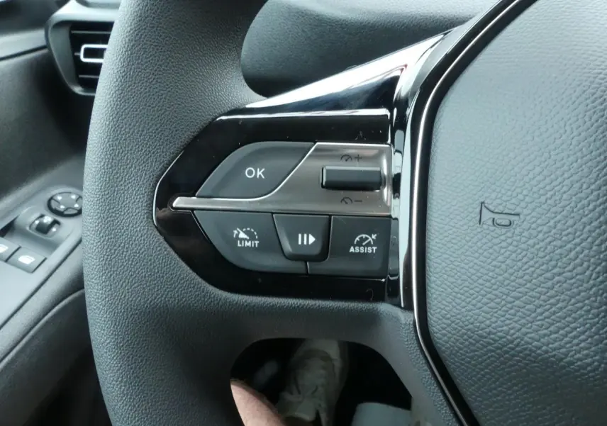 Gros plan sur le volant côté gauche du Peugeot Partner blanc 2025 avec commandes de régulateur et aide à la conduite.