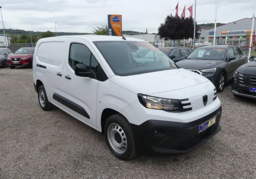 Peugeot Partner blanc en 3/4 avant droit, avec boucliers noirs et jantes tôles grises, stationné en extérieur.