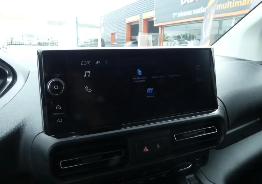 Vue intérieure du tableau de bord du Peugeot Partner blanc, avec écran tactile 10 pouces et commandes de climatisation.
