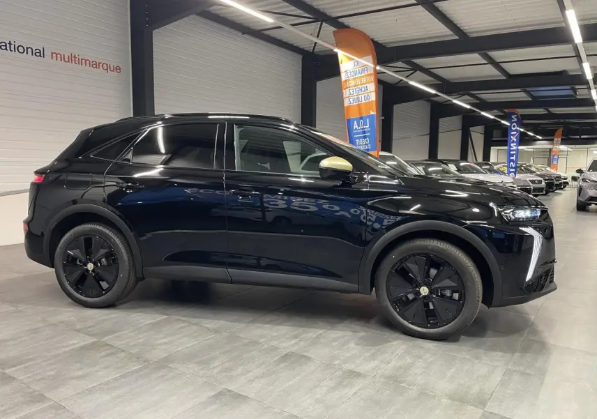 Vue de profil droit du DS7 Crossback noir métallisé avec coques de rétroviseurs dorées satinées en intérieur showroom.