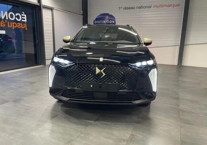 Vue avant d'un DS7 Crossback noir métallisé avec calandre DS Wings et feux LED verticaux allumés en showroom.