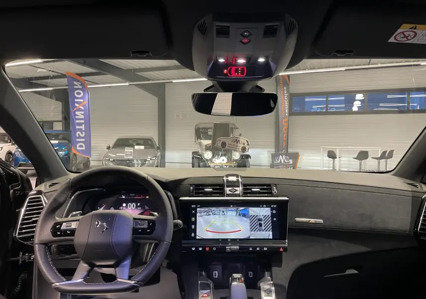 Vue intérieure avant du DS7 Crossback noir métallisé, volant cuir perforé et écran tactile affichant la caméra de recul.