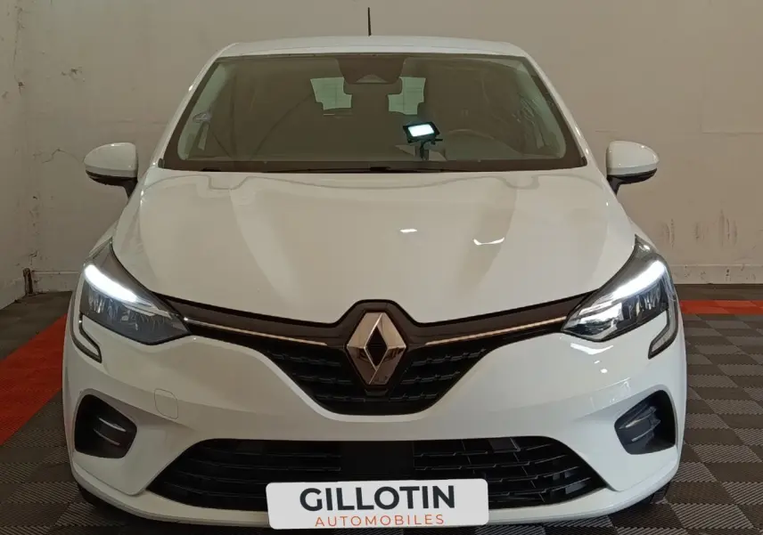 Vue frontale d'une Renault Clio Business blanche avec feux LED allumés et calandre noire distinctive.