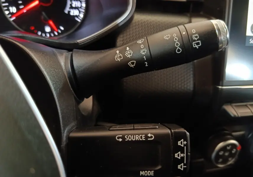 Gros plan sur les commandes au volant noir de la Renault Clio Business, avec tableau de bord partiellement visible.