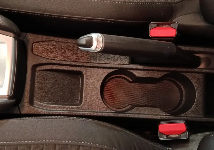 Vue rapprochée de la console centrale noire avec frein à main et porte-gobelets de la Renault Clio Business blanche.