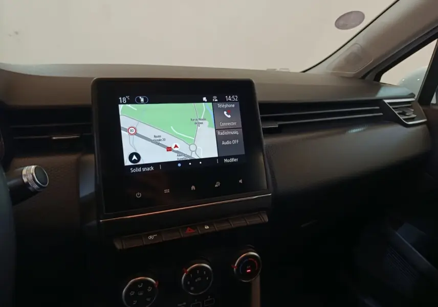 Vue intérieure du tableau de bord de la Renault Clio Business blanc, avec écran tactile de navigation affiché.