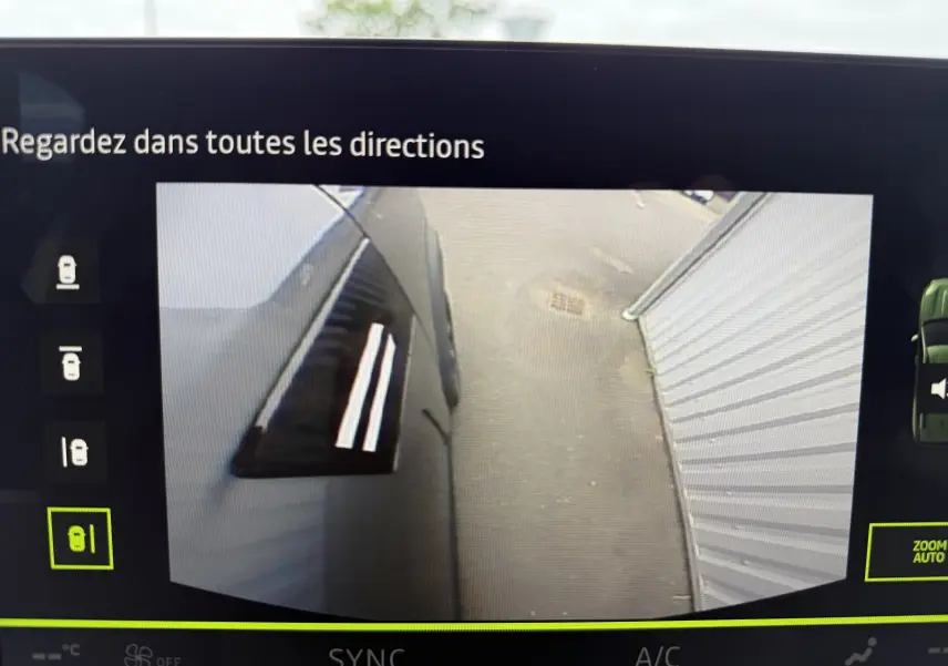 Vue caméra latérale gauche du Dacia Bigster gris schiste métal, montrant la porte et le sol à côté d'un mur blanc.