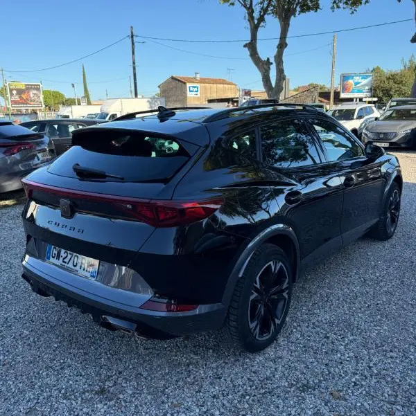 Vue 3/4 arrière droite d'une CUPRA Formentor noir brillant 2024, avec feux arrière étirés et jantes noires distinctives.