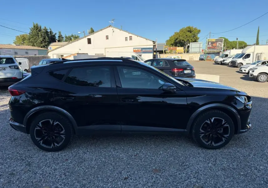 Profil latéral gauche d'un CUPRA Formentor noir 2024, SUV hybride avec jantes noires au design sportif, sur parking extérieur.