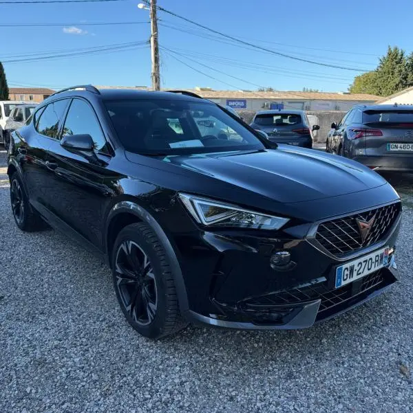 SUV CUPRA Formentor noir en 3/4 avant droit, avec calandre distinctive et jantes noires, stationné sur un sol gravillonné.