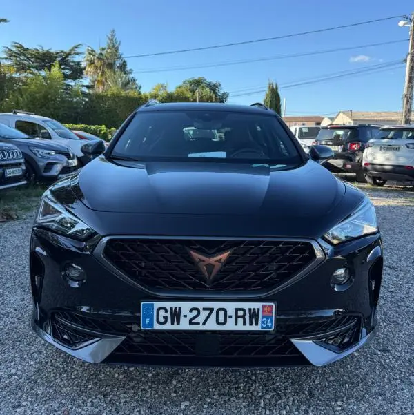 Vue avant d'un CUPRA Formentor noir 2024 avec calandre noire et logo cuivre, sur un parking extérieur ensoleillé.