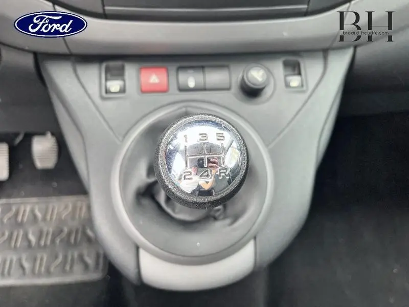 Gros plan sur le levier de vitesses manuel chromé d'un Peugeot Partner Tepee blanc, avec console centrale grise visible.