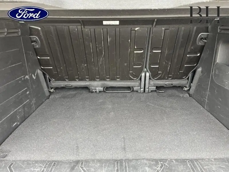 Coffre vu de l'intérieur d'un Peugeot Partner Tepee blanc Banquise, montrant la banquette arrière rabattue et l'espace de chargement.