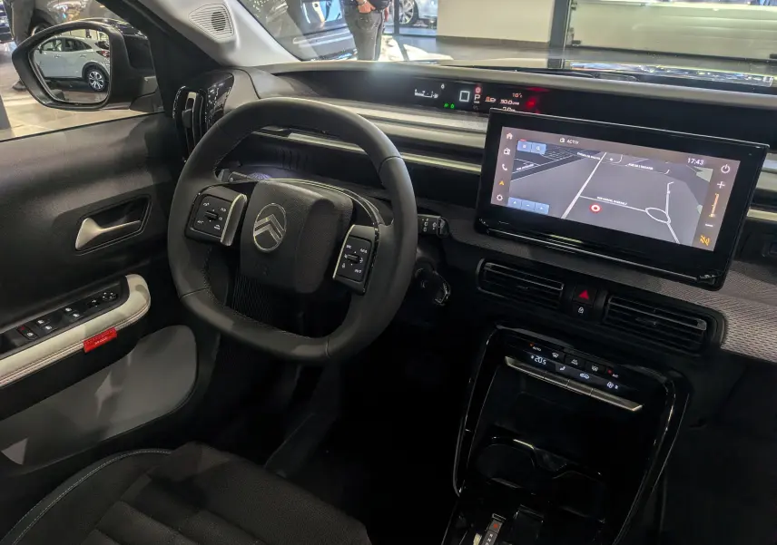 Intérieur du Citroën C3 Aircross hybride 2025, vue côté conducteur sur volant, écran tactile et tableau de bord numérique.
