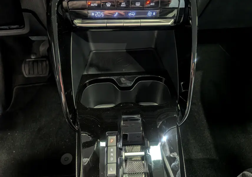 Gros plan sur la console centrale noire brillante de la Citroën C3 Aircross hybride 2025 avec commandes climatisation et levier de boîte auto.