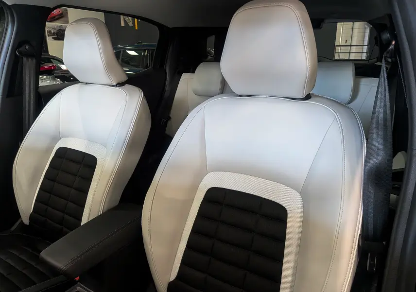 Gros plan sur les sièges avant en cuir bi-ton blanc et noir du Citroën C3 Aircross Hybride 2025.