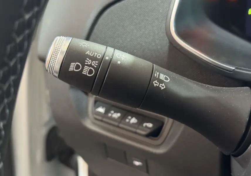 Gros plan sur la commande des phares et clignotants dans l'habitacle d'une Renault ZOE blanche de 2020.