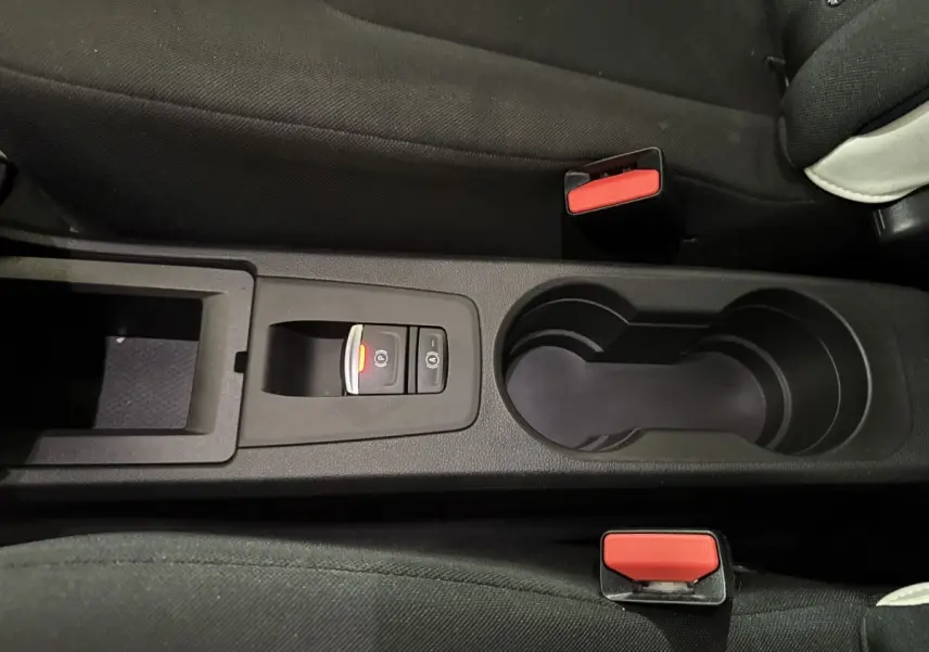 Vue rapprochée de la console centrale noire avec frein à main électrique et porte-gobelets de la Renault ZOE blanche 2020.