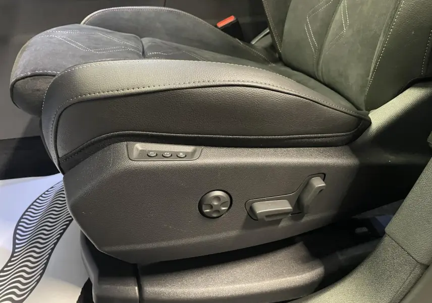 Détail du siège avant conducteur en Alcantara noir profond avec commandes électriques sur le côté gauche.