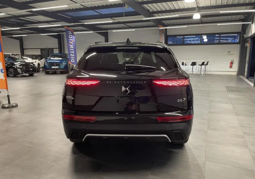 Vue arrière d'un DS7 Crossback noir métallisé avec feux arrière LED 3D allumés dans un showroom.