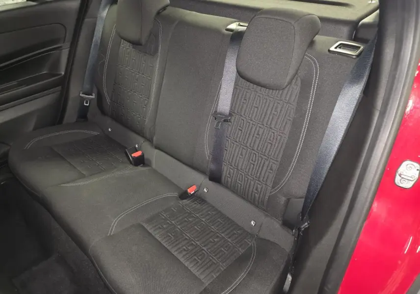Vue intérieure arrière droite de la banquette noire avec motifs FIAT, ceinture et portière rouge visible du FIAT 600 2024.