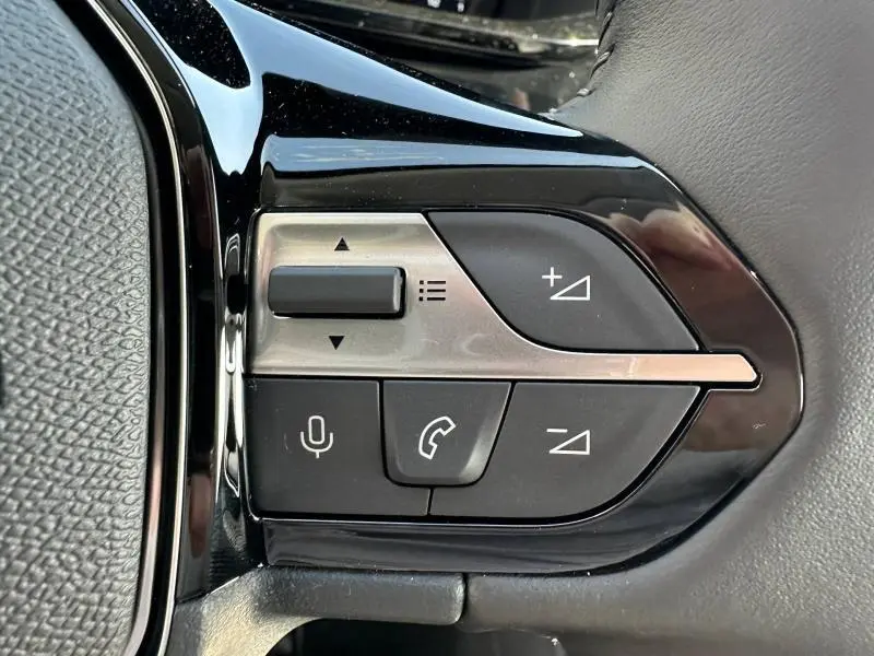 Gros plan sur les commandes multifonctions du volant côté gauche du Peugeot 308 gris Artense, boutons volume et appel.