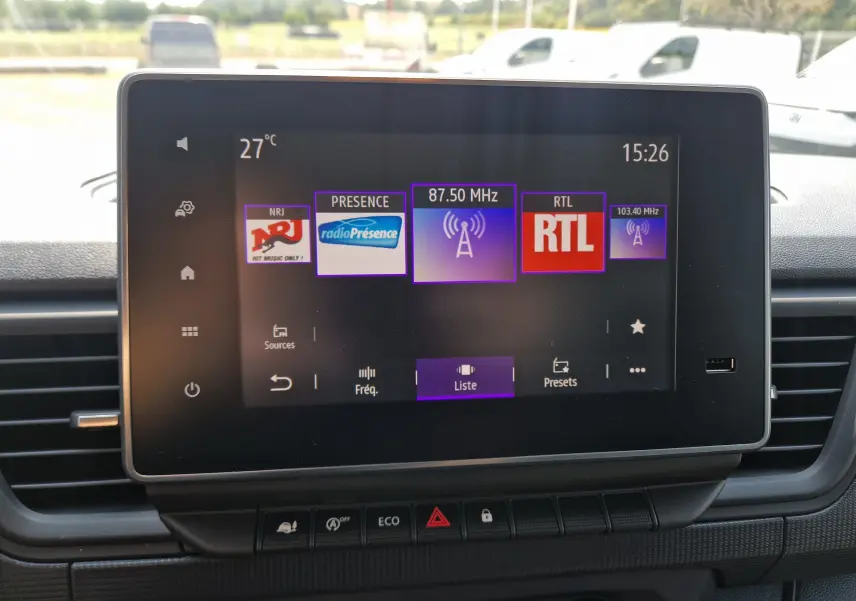 Écran tactile central du Renault Trafic Fourgon 2026 affichant les radios NRJ, Présence et RTL, avec commandes en dessous.