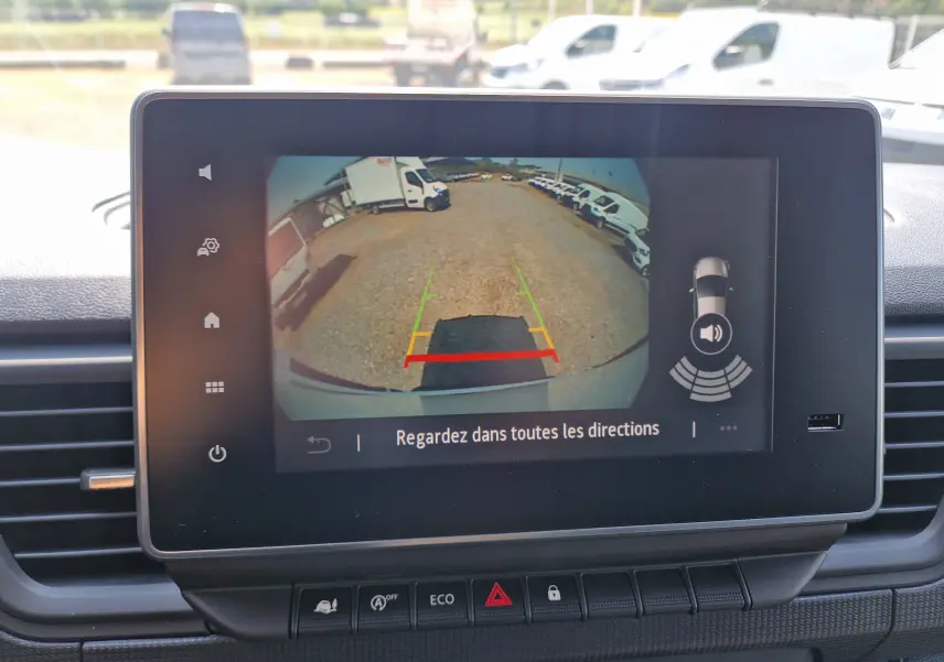 Écran tactile montrant la caméra de recul du Renault Trafic blanc, vue arrière avec lignes de guidage colorées.