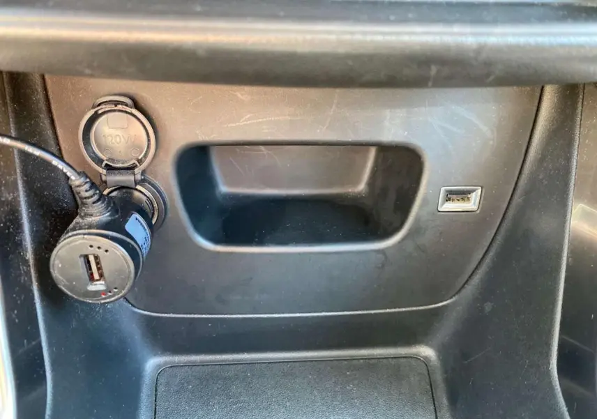 Prise USB et allume-cigare avec adaptateur dans le compartiment central d'une Citroën C3 Aircross 2023 gris Artense.