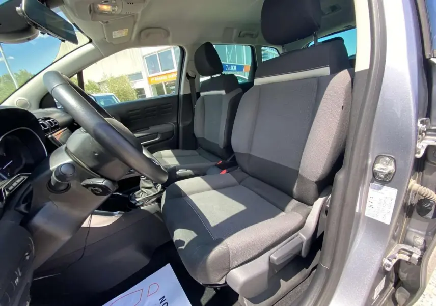 Intérieur avant droit du Citroën C3 Aircross gris Artense, sièges tissu bicolore et volant noir visible.
