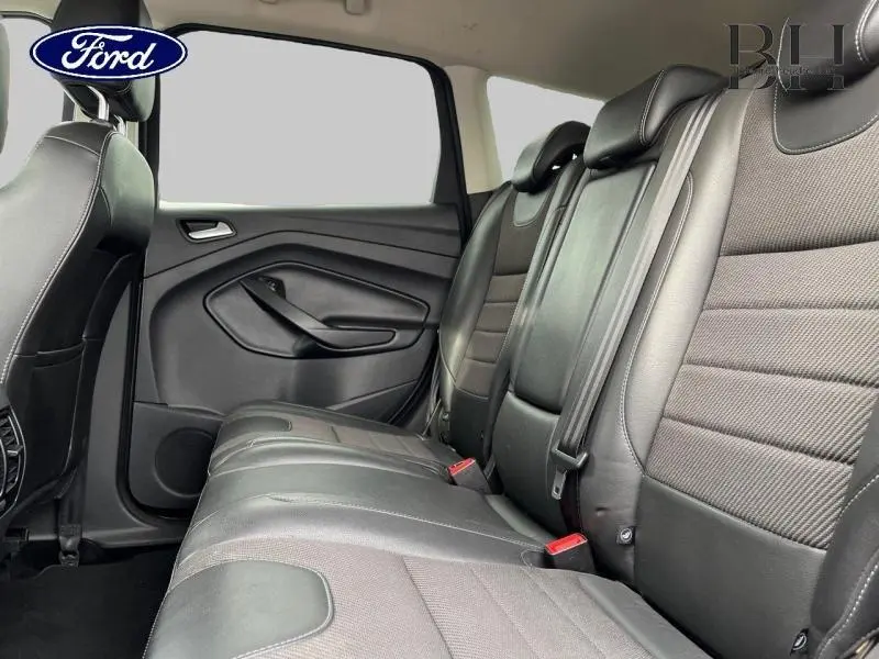 Vue latérale droite de la banquette arrière en cuir/tissu noir du Ford Kuga 2015, avec ceintures de sécurité visibles.
