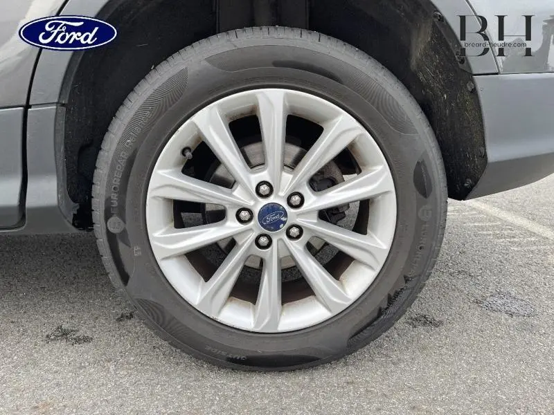 Gros plan sur la roue avant gauche avec jante alu du Ford Kuga gris Magnetic de 2015.