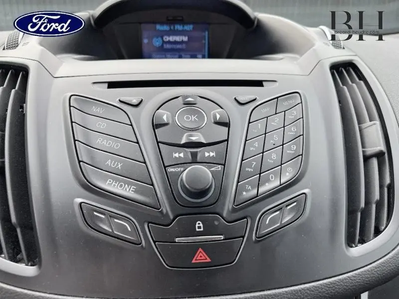 Vue rapprochée du tableau de bord noir du Ford Kuga 2015 avec commandes audio et écran multifonction.