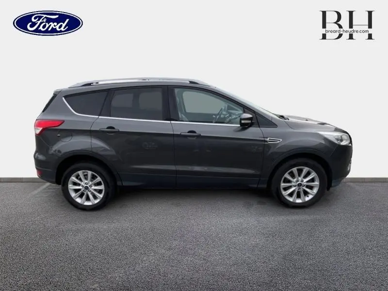 Profil droit d'un Ford Kuga 2.0 TDCi 150ch Titanium gris Magnetic avec jantes alu et vitres teintées.