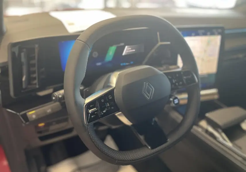 Vue intérieure centrée sur le volant noir de la Renault Rafale 2025 avec tableau de bord numérique et écran tactile.